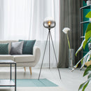 Piantana Maxy a treppiede in metallo nero e vetro fumé in soggiorno elegante e moderno